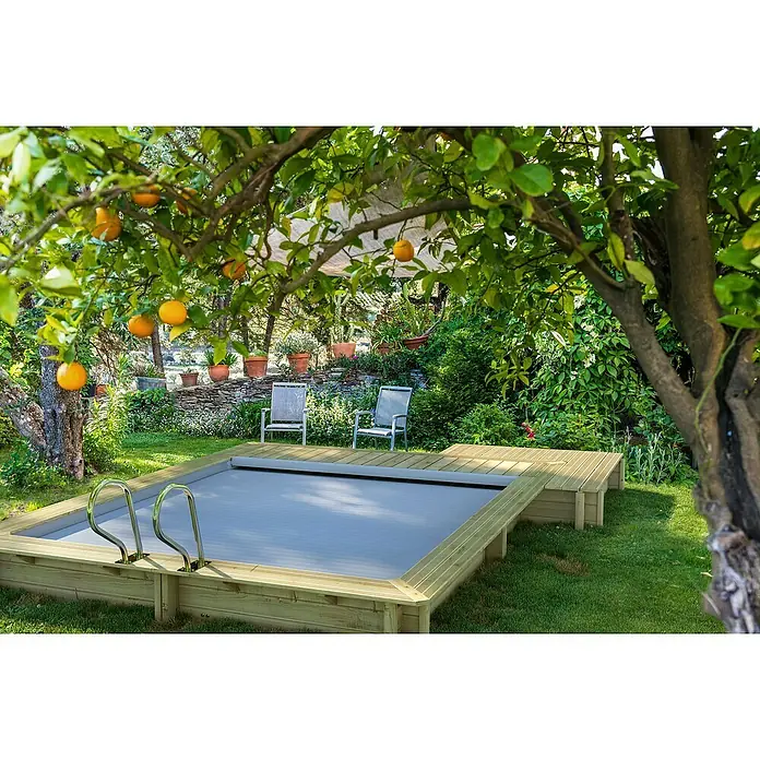 myPool Holz-Pool Urban - 486 x 401 x 133 cm, 11.000 l, Braun, Grau - Ein ebenerdiger Pool mit Holzrahmen und einer grauen Poolabdeckung, umgeben von grüner Vegetation.
