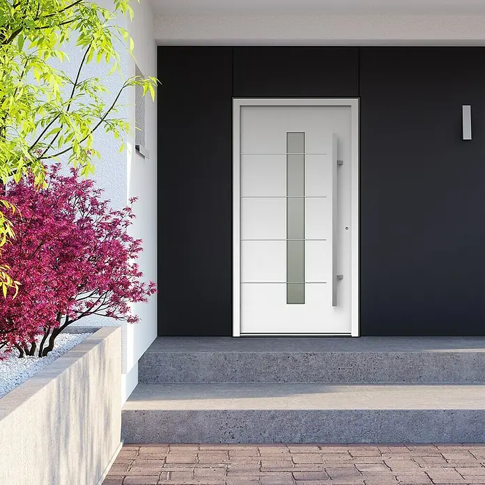 Gerda Haustür Thermo Prime 75 Ulm - 110 x 210 cm, DIN Anschlag: Rechts, Weiß, Details in Edelstahl - Moderne Haustür in Weiß mit schlichtem Design und senkrechtem Glaseinsatz, umgeben von dunkler Fassade und grüner Bepflanzung.