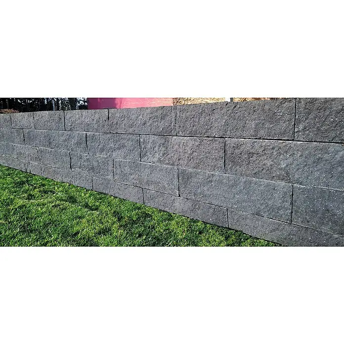 Christoph Mauerstein Rustikalblock - 50 x 12,5 x 14 cm, Kristall/Anthrazit, Beton - Nahaufnahme einer grauen Steinmauer mit etwas Rasen davor, die die Textur und das Baumaterial der Mauer hervorhebt.
