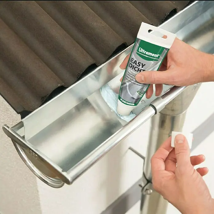 Ultrament Reaktivabdichtung Easy Dicht - 180 g, 1-komponentig - Eine Person, die die Ultrament Easy Dicht Dichtmasse auf eine Dachrinne aufträgt, um undichte Stellen abzudichten und die Lebensdauer zu verlängern.