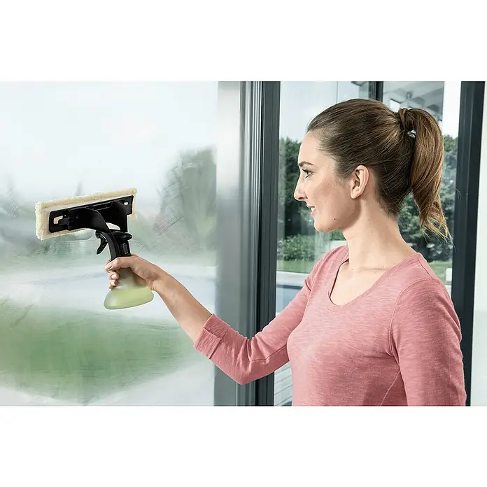 Kärcher Sprühflaschen-Set rund - 4 -tlg. - Frau putzt Fenster mit Kärcher Fenstersauger für streifenfreie Sauberkeit. Das Gerät sprüht und wischt in einem Schritt.