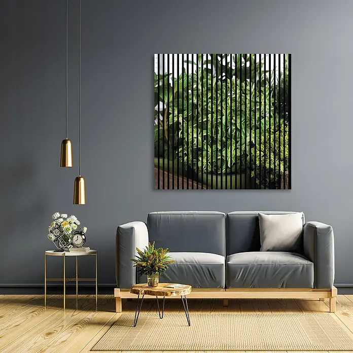 Profiles and more Akustikpaneel Oregano - 1.195 x 1.133 x 19 mm - Eine stilsichere Wohnzimmerszene mit einem grauen Sofa, einem goldenen Beistelltisch und einem abstrakten Pflanzenbild an der Wand.