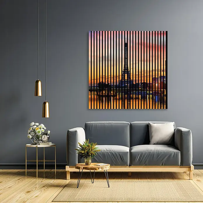 Profiles and more Akustikpaneel Paris - 1.195 x 1.133 x 19 mm - Abstraktes Wandbild von Paris mit dem Eiffelturm bei Sonnenuntergang, das über einem grauen Sofa in einem modernen Wohnzimmer hängt.