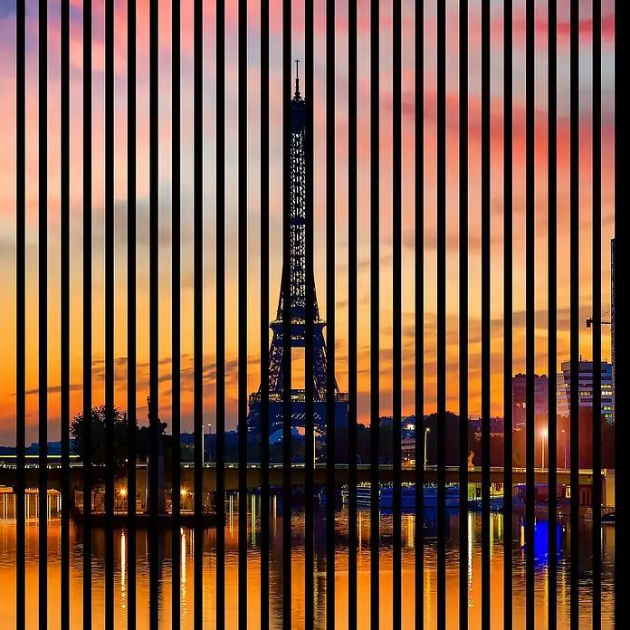 Profiles and more Akustikpaneel Paris - 1.195 x 1.133 x 19 mm - Abstraktes Bild des Eiffelturms bei Sonnenuntergang, kunstvoll durch vertikale schwarze Balken unterbrochen.