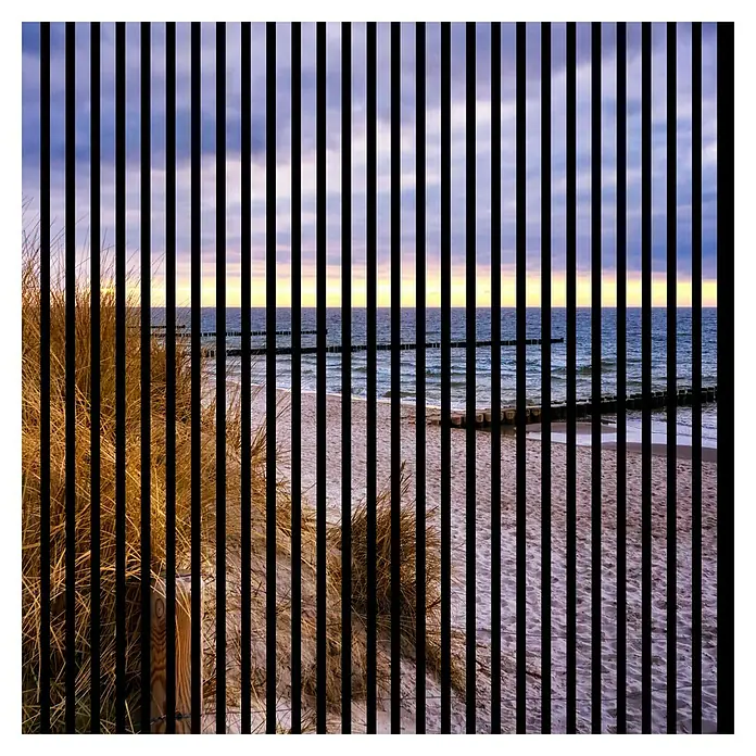 Profiles and more Akustikpaneel Ostsee - 1.195 x 1.133 x 19 mm - Blick auf einen Sandstrand mit Düne, unterbrochen durch vertikale schwarze Linien, die eine interessante visuelle Verzerrung erzeugen.