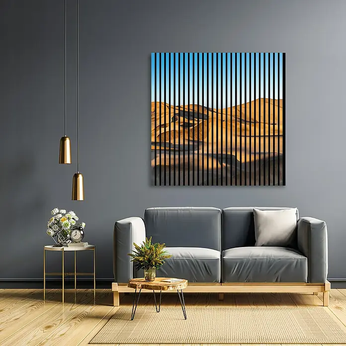 Profiles and more Akustikpaneel Dünen - 1.195 x 1.133 x 19 mm - Ein modernes Wohnzimmer mit einem grauen Sofa, einem Beistelltisch mit Blumen und einer abstrakten Wüstenbild-Dekoration an der Wand.