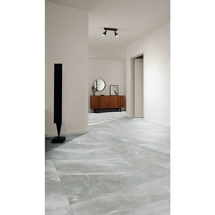 Feinsteinzeugfliese Pulpis - 100 x 100 cm, Grau, Matt - Modernes Interieur mit stilvollem grauem Marmorboden, minimalistischer Dekoration und einer Holzanrichte im Hintergrund.