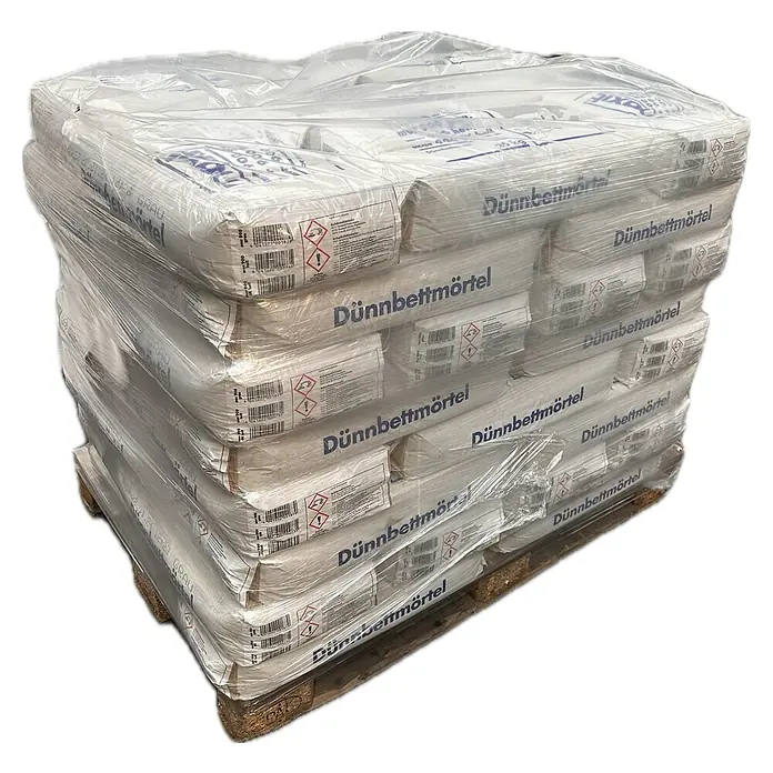 Maxit Dünnbettmörtel mur 900 - 25 kg - Palett mit Säcken Dünnbettmörtel, verpackt in Plastikfolie. Die Säcke sind weiß und mit dem Schriftzug "Dünnbettmörtel" versehen.