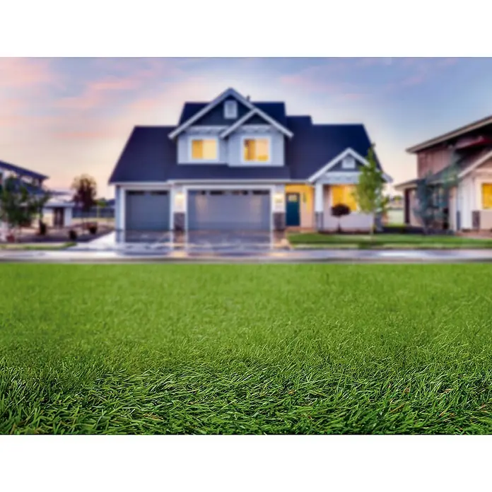 Césped artificial Chile - 5 x 1 m, Altura del pelo: 15 mm, 21.000 puntadas/m² - Casa con césped bien cuidado en primer plano, fondo borroso con otras casas y cielo del atardecer.