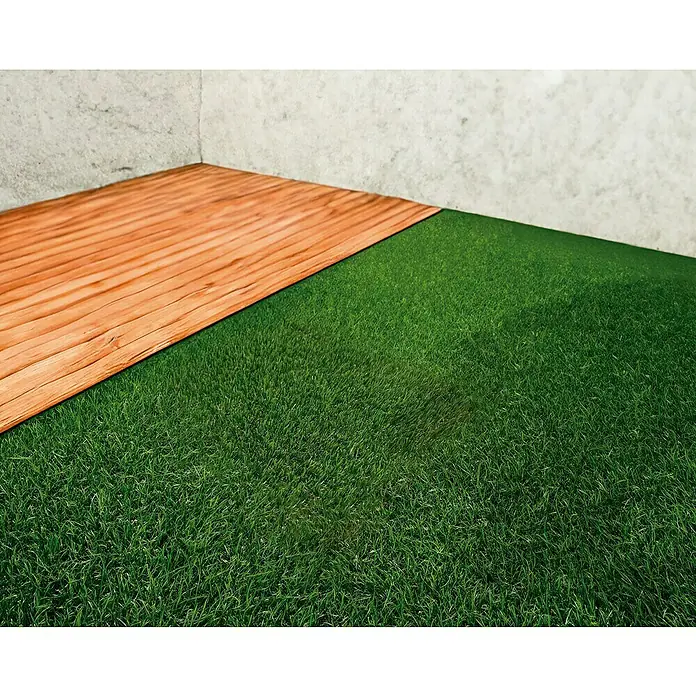 Césped artificial New Perú - 5 x 1 m, Altura del pelo: 25 mm, 16.800 puntadas/m² - Primer plano de una terraza de madera que linda con césped artificial contra una pared de concreto, resaltando las texturas.