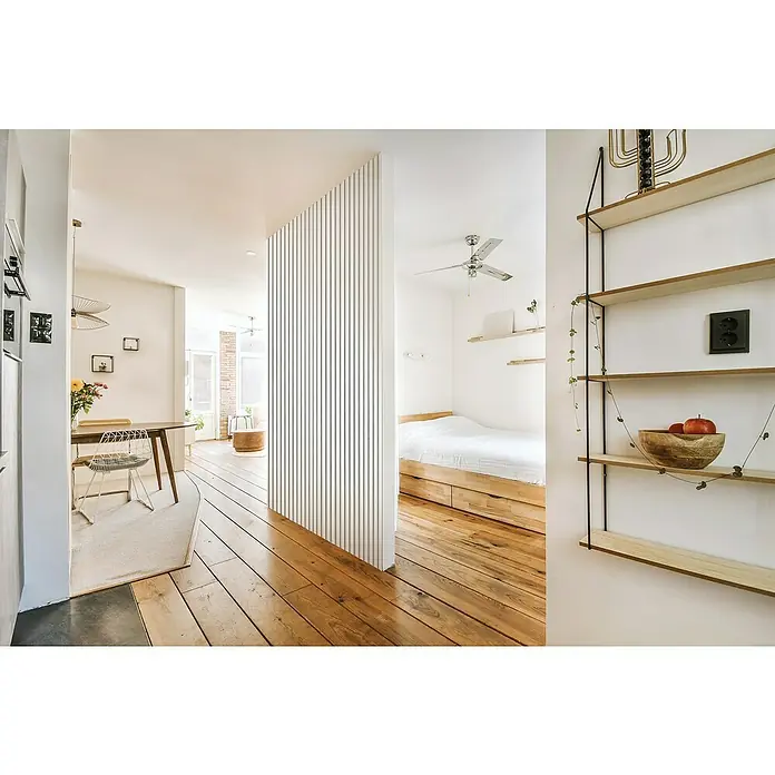 FibroTech Akustikpaneel Unika 25 - White Platinum, 2.440 x 600 x 22 mm - Helle Wohnung mit Holzböden, minimalistischen Regalen mit Dekoration und einem gemütlichen Schlafbereich.