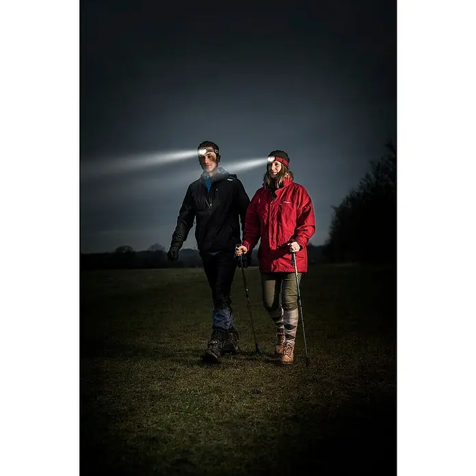Energizer Linterna frontal - 4 x 4,5 x 7,3 cm, 300 lm, IPX4 - Una pareja camina de noche con linternas frontales iluminando su camino. Las potentes linternas aseguran una navegación segura en la oscuridad.