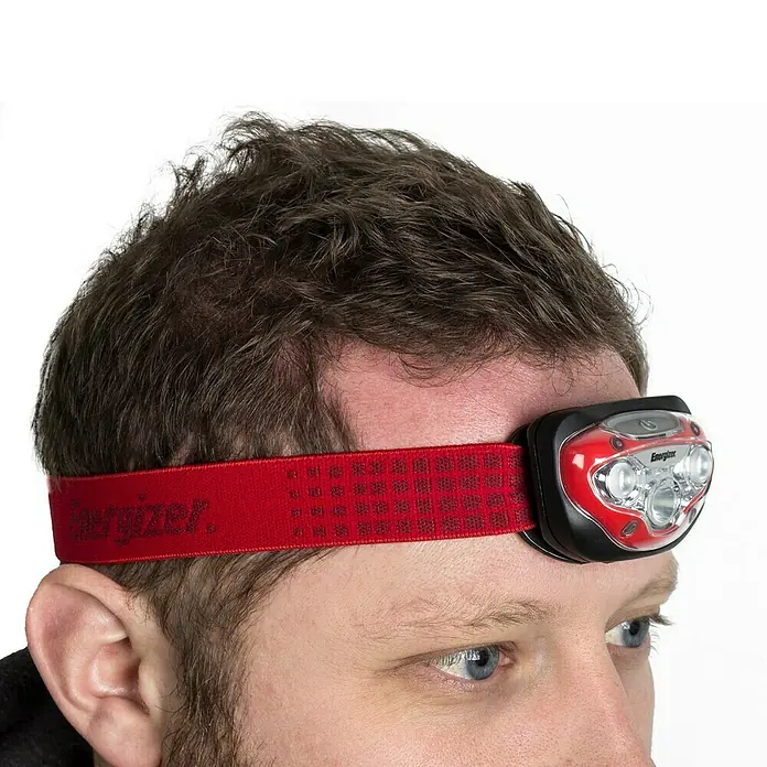 Energizer Linterna frontal - 4 x 4,5 x 7,3 cm, 300 lm, IPX4 - Primer plano de una persona con un frontal rojo Energizer, fijado en la frente.