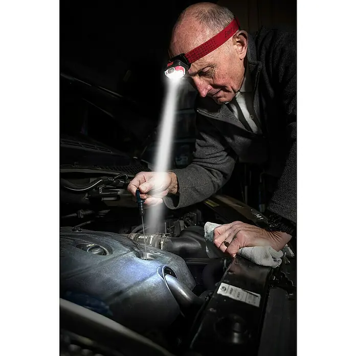 Energizer Linterna frontal - 4 x 4,5 x 7,3 cm, 300 lm, IPX4 - Hombre revisando el aceite del coche con linterna frontal Energizer. La luz ilumina el motor, ofreciendo visibilidad óptima.