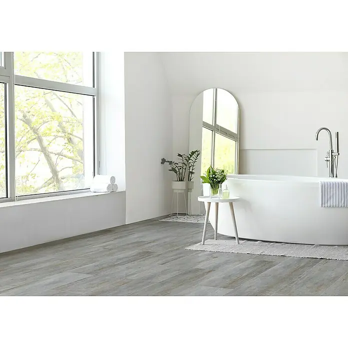 Feinsteinzeugfliese Allora - 30 x 60,4 cm, Grau, Matt - Elegantes Badezimmer mit freistehender Badewanne, großem Spiegel und hellen Holzböden, das ein Gefühl von Ruhe und modernem Design vermittelt.