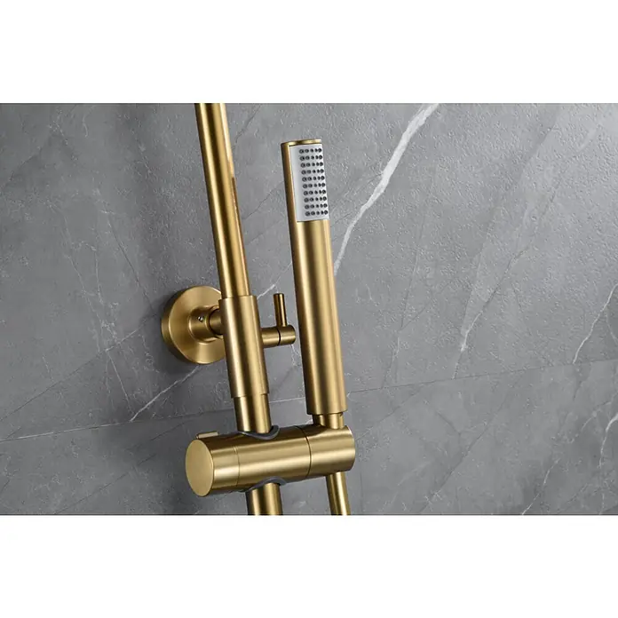 Imex Génova Sistema de ducha - Grifo termostático, Oro - Primer plano de una barra de ducha dorada con ducha de mano sobre una pared de mármol gris. Diseño de baño exquisito con accesorios de alta calidad.