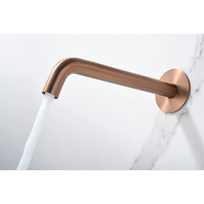 Imex Génova Grifo de lavabo empotrado - Oro rosa - Grifo de pared moderno de cobre con agua corriente sobre una pared de mármol. Presenta un diseño elegante y minimalista.