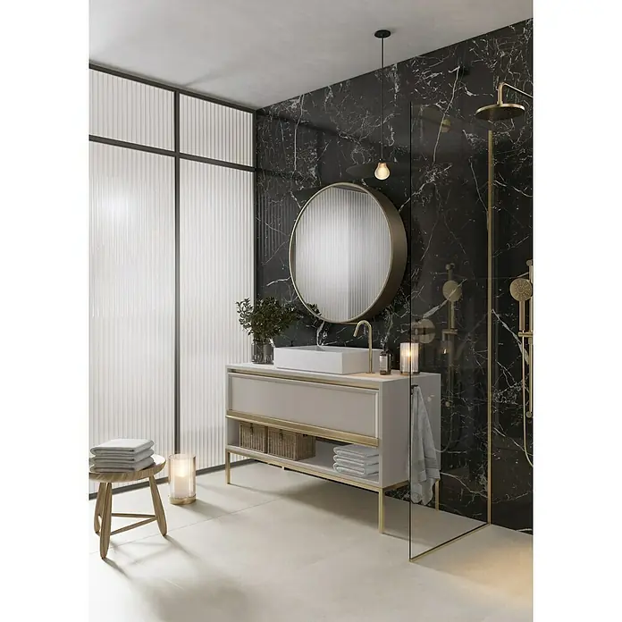 Feinsteinzeugfliese Sombra - 59,7 x 59,7 cm, Schwarz, Glänzend - Elegantes Badezimmer-Interieur mit Marmorwand, Waschtisch mit goldenen Akzenten, rundem Spiegel und stilvoller Beleuchtung für ein luxuriöses Ambiente.