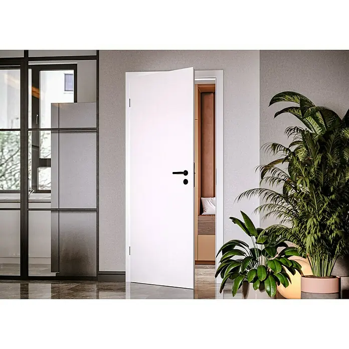 Invado Zimmertür ND1 - 860 x 2.110 mm, DIN Anschlag: Links, Verkehrsweiß matt, Röhrenspan - Weiß lackierte Innentür mit schwarzen Beschlägen, die einen Einblick in einen stilvollen Raum bietet, neben üppigen Zimmerpflanzen.