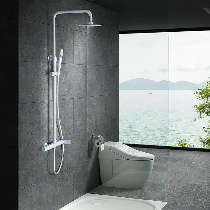Imex Dinamarca Sistema de ducha - Grifo monomando, Blanco - Elegante baño con sistema de ducha blanco y un moderno inodoro. Los azulejos grises y la vista al mar crean un ambiente lujoso.