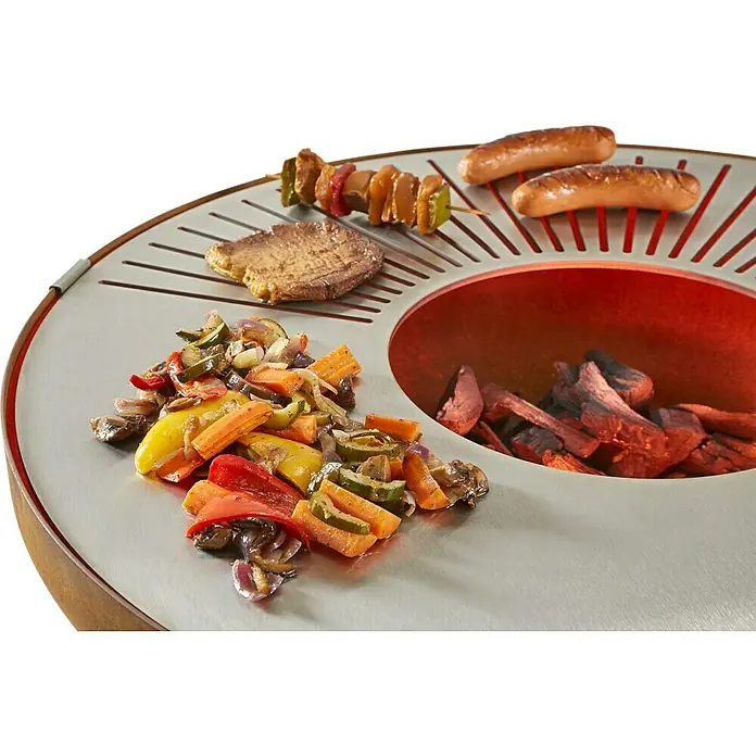 Kingstone Plancha-Grill - Ø x H: 80 x 98 cm, Rostbraun - Grill mit verschiedenen Lebensmitteln wie Würstchen, Gemüse, Fleisch und Spießen auf dem Grillrost, Holzkohle im Inneren.
