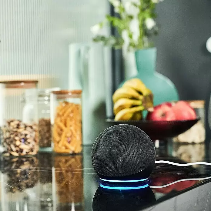 Set de cerradura electrónica Retrofit DiY - Gris, Número de componentes: 3 ud. - Un altavoz inteligente negro de tela con anillo de luz azul brillante en la encimera de una cocina.