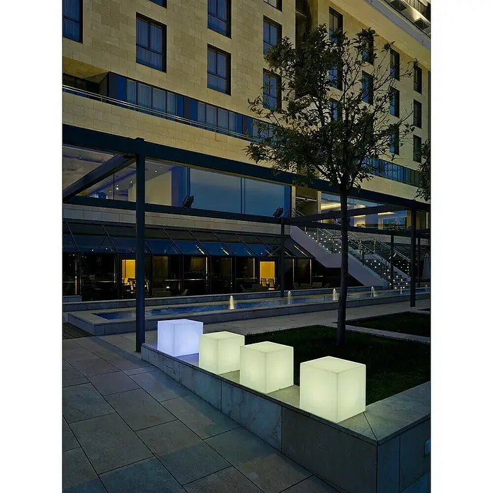 Starlux Cubo solar LED Gopi 32 - 32 x 32 x 32 cm - Escena atmosférica con asientos cúbicos iluminados en primer plano, creando un ambiente moderno y acogedor.