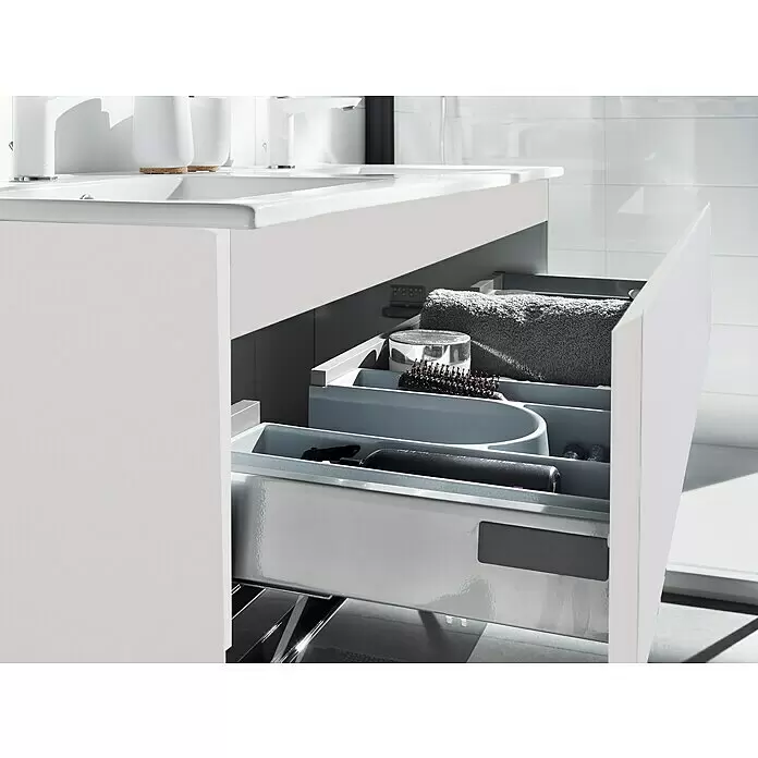 Camargue Espacio Waschtischunterschrank - 120 x 46 x 60 cm, 2 Schubkästen, Gama anthrazit glänzend - Weißer Badezimmerschrank mit geöffneter Schublade, die graue Organizer mit Pflegeprodukten zeigt.