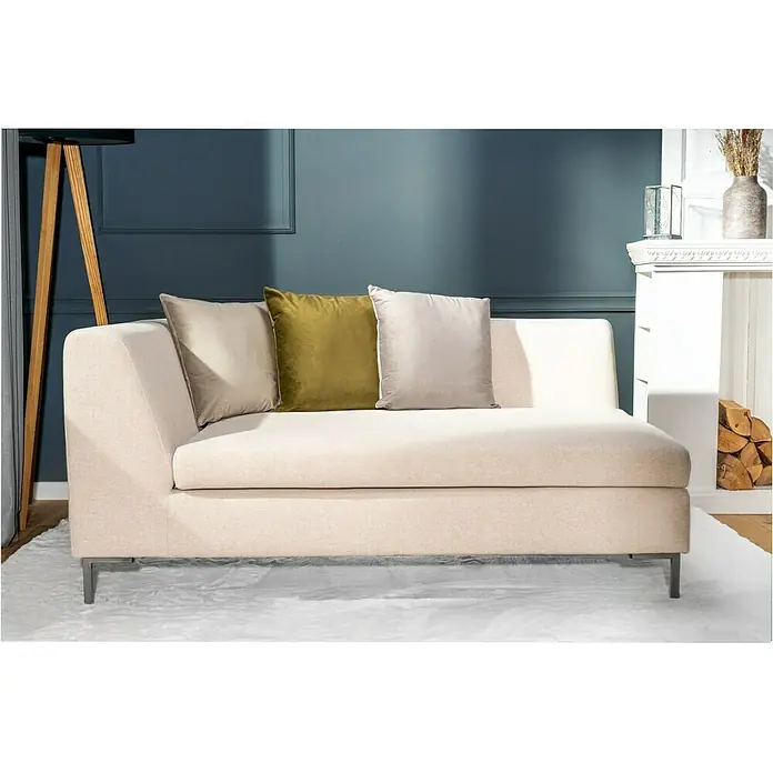 Kissen Finja - Driftwood, 45 x 45 cm, 100 % Polyester - Beige Ottomane mit stilvollen Kissen vor blauem Hintergrund. Das Sofa hat minimalistische Metallbeine und bietet komfortable Sitzgelegenheiten.
