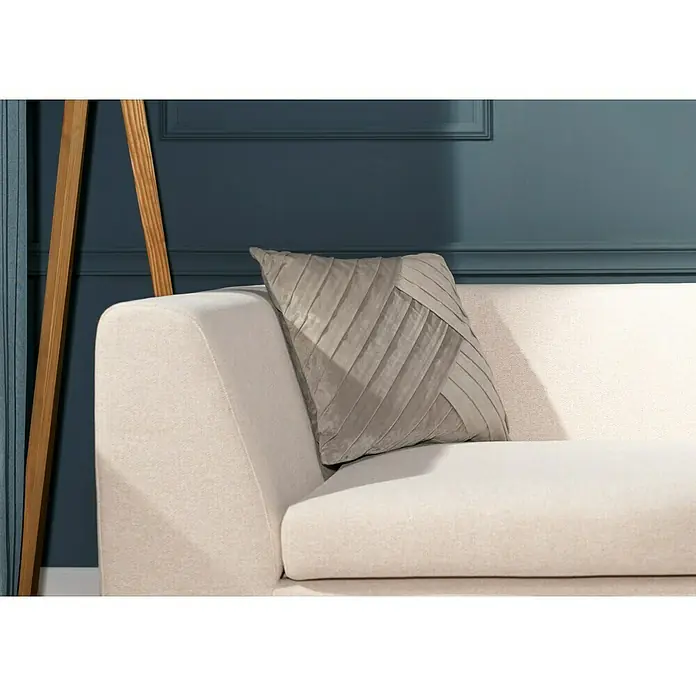 Kissen Hannah - Pumice Stone, 45 x 45 cm, 100 % Polyester - Nahaufnahme eines beigen Sofas mit einem dekorativen, grauem Kissen mit Faltenmuster vor einer dunkelblauen Wand.