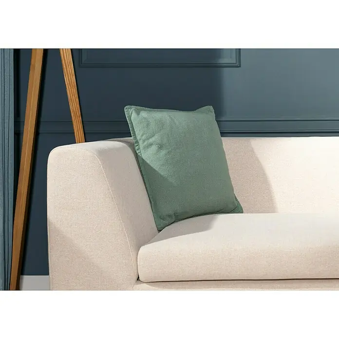 Kissen Bona - Jade, 45 x 45 cm, 100 % Baumwolle - Nahaufnahme eines hellbeigen Sofas mit einem grünen Kissen, das eine gemütliche und stilvolle Wohnatmosphäre erzeugt.