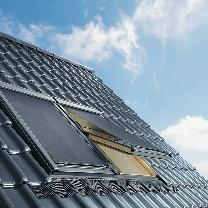 Velux Dachfenster-Markise Haltekrallen MHL 100 5060 - Farbe: Uni Schwarz - 5060, Manuell - Dachfenster mit Rollladen auf einem Dach mit Ziegeln, das eine effektive Beschattung bietet und die Raumtemperatur reguliert.