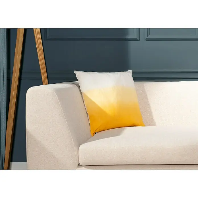 Kissen Rutger - Golden Glow, 45 x 45 cm, 100 % Baumwolle - Ein quadratisches, weiß-gelb schattiertes Kissen liegt dekorativ auf einem hellen Sofa und setzt einen farblichen Akzent im Raum.