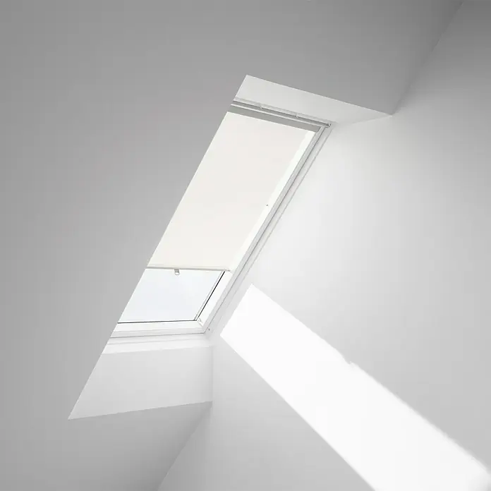 Velux Dachfensterrollo Haltekrallen RHL MK00 1086 - Farbe: Hellbeige - 1086, Farbe Schiene: Aluminium, Manuell - Helles Dachfenster mit Rollo in einem weißen Dachzimmer. Das Fenster sorgt für viel Tageslicht und frische Luft im Raum.
