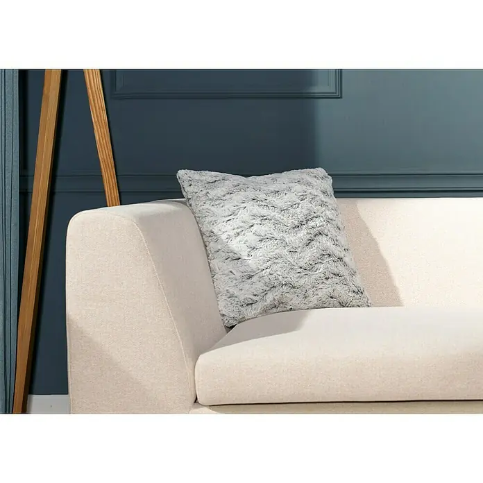 Kissen Smooth - Schwarz, 45 x 45 cm, 100 % Polyester - Ein quadratisches, graues Kissen mit Fellstruktur liegt auf einem beigen Sofa vor einer blaugrünen Wand. Dekoratives Wohnaccessoire.