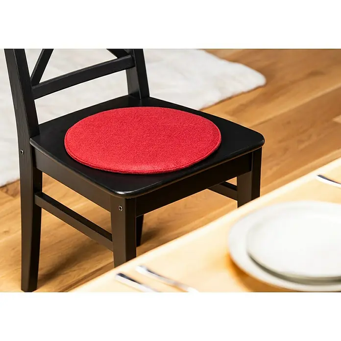 Sitzkissen rund Carl - Ø x H: 35 x 2 cm, Weinrot, 100 % Polyester - Ein schwarzer Stuhl mit einem runden, roten Sitzkissen darauf, der Komfort und Stil in jeden Essbereich bringt.
