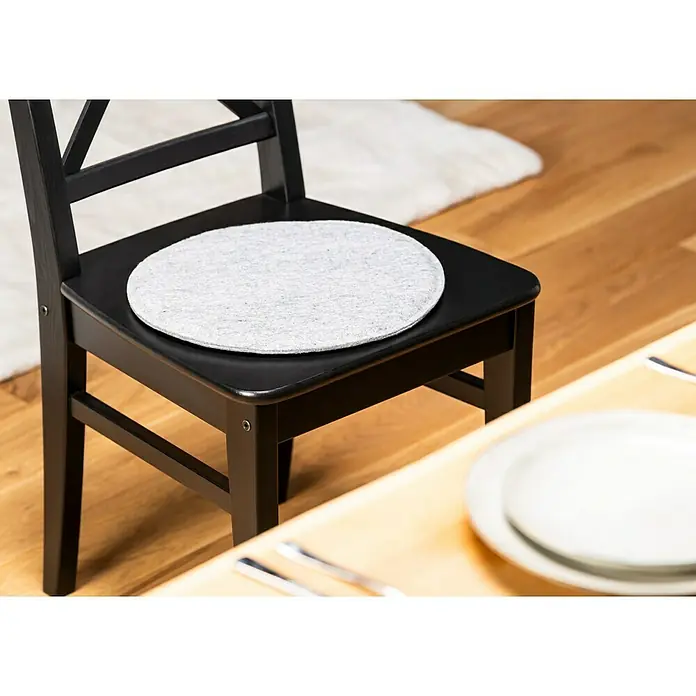 Sitzkissen rund Carl - Ø x H: 35 x 2 cm, Grau, 100 % Polyester - Schwarzer Holzstuhl mit einer runden, hellgrauen Sitzauflage, der für zusätzlichen Komfort beim Sitzen sorgt.