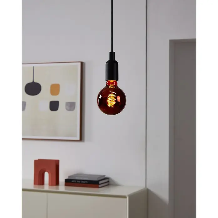Eglo Bombilla LED - E27, Intensidad regulable, Blanco cálido, 30 lm, 4 W - Primer plano de una bombilla Edison colgante con vidrio rojo y un accesorio negro, que emana un brillo cálido y decorativo.