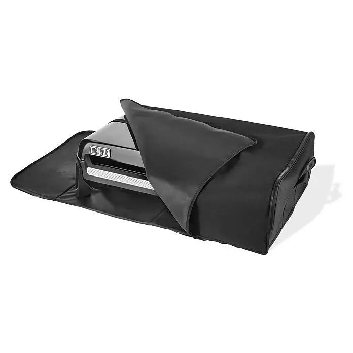 Weber Transporttasche - L x B x H: 59 x 89 x 26,5 cm, Polyester, Passend für: Weber Plancha Grills Slate 43 und 56 - Schwarzer Weber-Grill, teilweise von seiner schwarzen Tragetasche bedeckt.