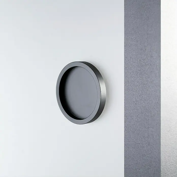 Room Plaza Loft + Mehr Griffmuschel-Set - Schwarz matt, Rund - Nahaufnahme eines runden, schwarzen Türgriffs an einer weißen Tür, der ein elegantes und modernes Design aufweist.
