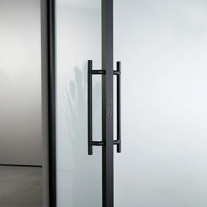 Room Plaza Loft + Mehr Stoßgriff-Set - Schwarz matt, 400 x 35 mm, Rund - Schwarzer Türgriff an einer modernen Glastür. Das minimalistische Design betont die klare Linienführung und hochwertige Verarbeitung der Tür.