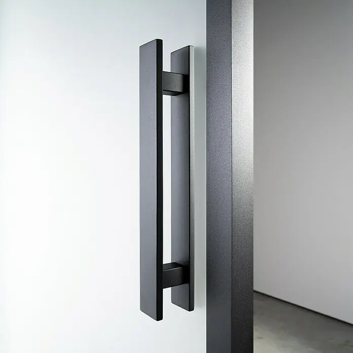 Room Plaza Loft + Mehr Griffstangen-Set - Schwarz matt, 350 x 40 mm, Eckig - Nahaufnahme eines modernen, rechteckigen Türgriffs aus Metall in dunkler Farbe, der an einer weißen Tür befestigt ist.