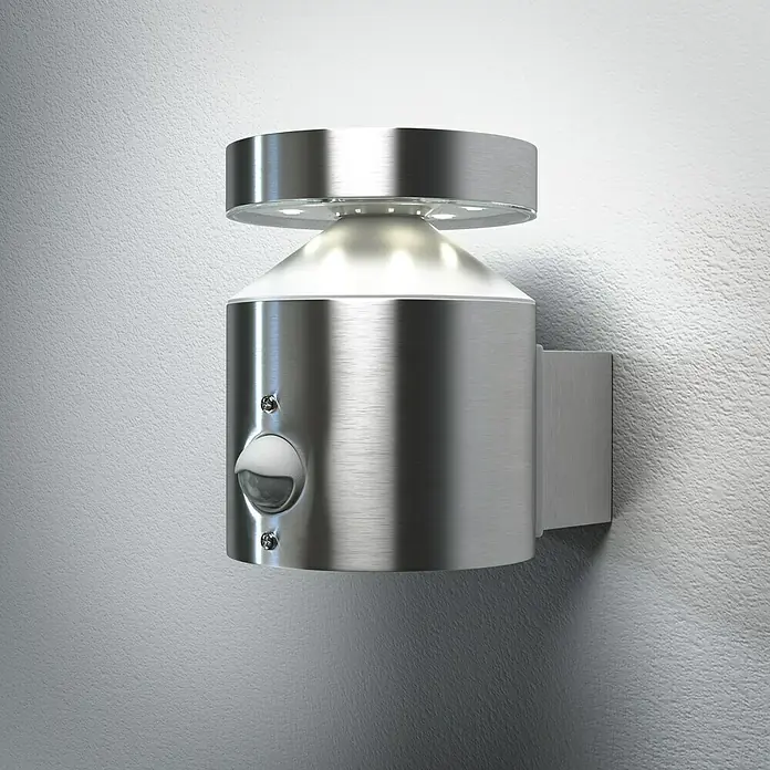 Ledvance LED-Sensor-Außenwandleuchte Wall - 6 W, L x B x H: 15 x 10,2 x 13,5 cm, Edelstahl, Warmweiß - Nahaufnahme einer modernen, silberfarbenen Wandleuchte mit Bewegungssensor, die ein helles, einladendes Licht ausstrahlt.