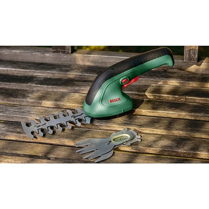 Bosch Akku-Gras- & Strauchschere EasyShear Akku-Gras- & Strauchschere - 3,6 V, Li-Ionen, 1 Akku, Schwertbreite: 8 cm - Die Bosch Akku-Grasschere mit ihren Aufsätzen auf einem Holztisch. Ein nützliches Werkzeug für die Gartenarbeit.