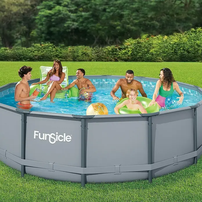 Funsicle Frame-Pool Oasis - Ø x H: 427 x 107 cm, Grau, 13.294 l - Ein "Funsicle"-Pool, gefüllt mit lachenden Menschen, die sich an einem sonnigen Tag vergnügen, umgeben von üppigem Grün.