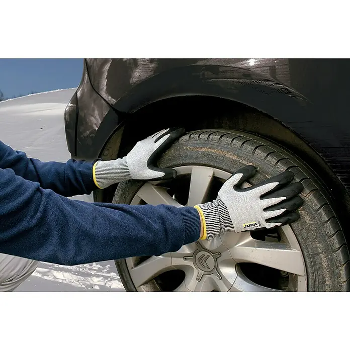 Juba Guantes de trabajo H4117 - Talla del guante: 8, Gris/Negro, 2 ud. - Primer plano de guantes de trabajo Juba usados por una persona que cambia un neumático de coche, ideales para trabajos de taller.