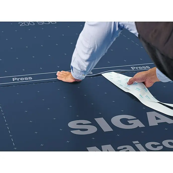 Siga Dachunterdeckbahn Majcoat 200 SOB - 20 m², 13,4 x 1,5 m, Polypropylen - Nahaufnahme von SIGA-Dichtungsband bei der Anwendung, ideal zum Abdichten und für Bauprojekte.