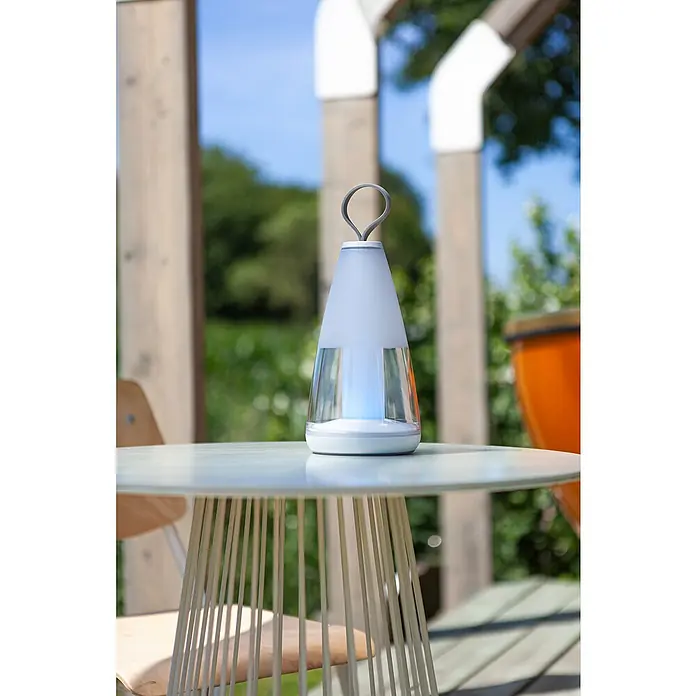 Lutec Akku-Tischleuchte PEPPER - 3 W, L x B x H: 12 x 12 x 29 cm, Weiß, RGBW - Tischleuchte mit Tragegriff auf einem Gartentisch. Das Licht hat ein stilvolles und modernes Design für den Außenbereich.