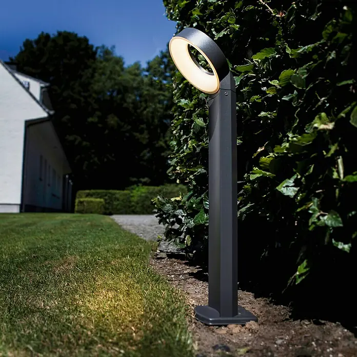 Lutec Sobremuro exterior Meridian - Color del marco: Gris oscuro, Blanco cálido, 21,3 x 18 x 58 cm - Una luz exterior moderna con diseño en forma de anillo ilumina un camino de jardín por la noche. La lámpara proporciona luz cálida.