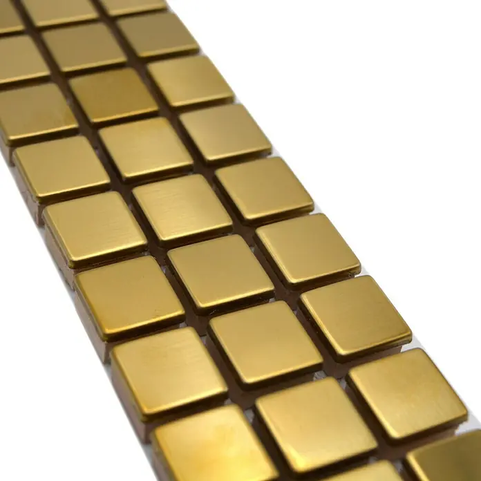 Fliesenbordüre Steel gestrichen YBO 15DG - 30 x 4,8 cm, Gold, Glänzend - Nahaufnahme von goldenen quadratischen Aufklebern, die auf einer transparenten Folie angeordnet sind, ideal für Bastelarbeiten und Dekorationen.